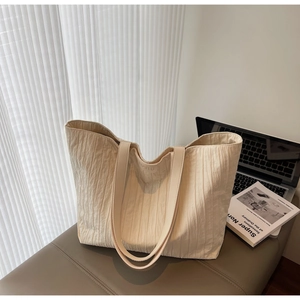 Detail of cream large tote bag featuring unique pleated texture and embossed logo