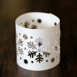 Detail of laser-cut snowflake patterns on white cardstock Christmas candle lantern cover