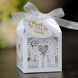 Close-up of white laser-cut hollow heart tree candy box with ribbon and thank you tag