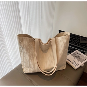 Detail of cream tote bag featuring pleated texture and logo interior branding