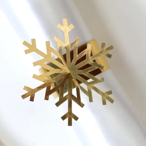 Macro shot of bright gold snowflake napkin ring with polished metal finish on white fabric