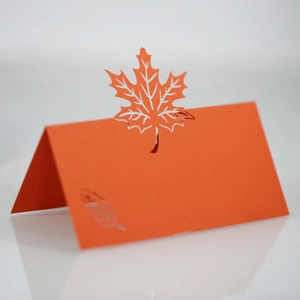 Close-up of laser-cut orange maple leaf place card with elegant embossed details