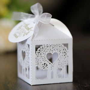 Macro detail of laser-cut tree box with heart patterns and white ribbon on wood