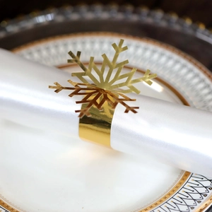 Close-up of golden snowflake napkin ring with hollow design on white satin napkin