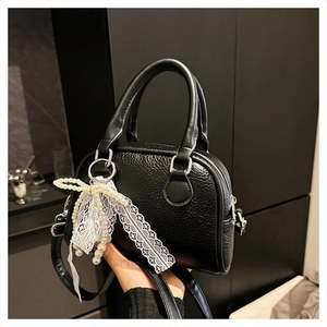 Detail of black lychee texture Boston bag featuring pearl and lace bow charm detail
