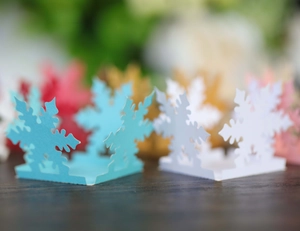 Close-up of laser-cut snowflake candy box card in multiple colors for party decor