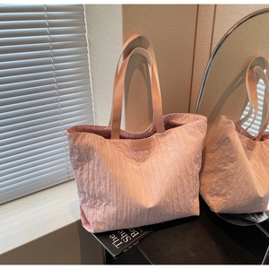 Detail of pink nylon tote bag with pleated texture and leather JUMAITU logo tag