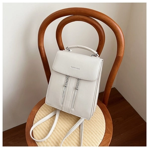 Detail of white leather backpack with Fashion & Bag logo on wooden chair background