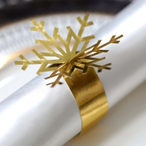Macro shot of gold snowflake napkin ring with intricate laser cutouts on white fabric