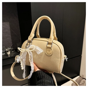 Detail of beige lychee pattern leather bag with lace bow and pearl decoration
