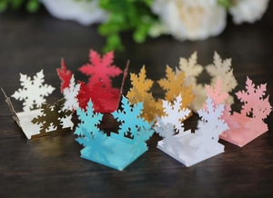 Detailed laser-cut snowflake cupcake wrappers in various colors for festive party decor