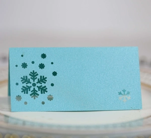 Close-up of laser-cut blue snowflake place card with pearlescent texture for weddings