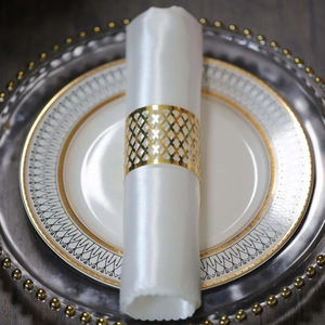 Close-up of golden hollow lattice napkin ring on elegant layered plates for wedding