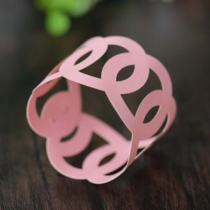 Macro shot of laser-cut pink paper napkin ring with a geometric pattern on wood