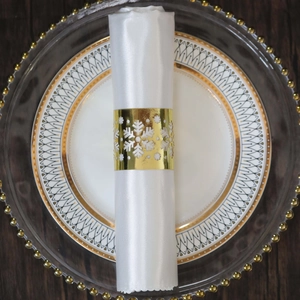Detail of golden snowflake napkin ring with intricate hollow design on white fabric