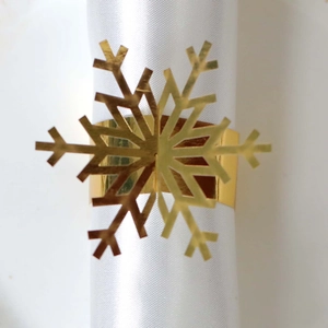 Close-up of golden snowflake napkin ring with polished metal finish on white cloth