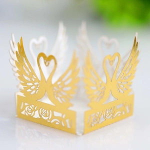 Macro view of gold laser-cut swan and rose paper wrapper for cupcakes or LED candles