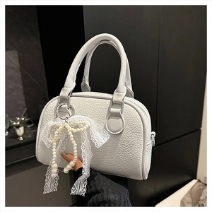 Detail of lychee pattern leather Boston bag with white lace bow and pearl pendant