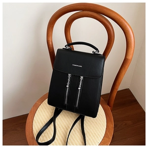 Detail of black faux leather backpack with silver zippers and Fashion & Bag logo text