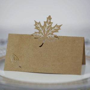 Detail of laser-cut maple leaf kraft paper place card standing on a white dining plate