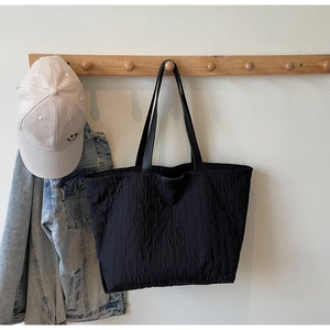 Detail of black tote bag featuring vertical pleated texture and JUMP logo patch