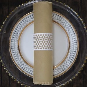 Detail of white laser-cut napkin ring with diamond cutout on gold silk cloth
