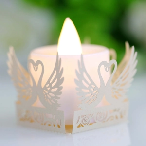 Macro shot of white LED candle with intricate laser-cut paper swan and rose holder