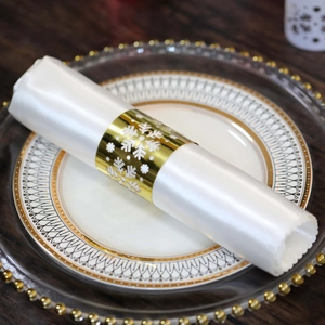 Close-up of golden snowflake napkin ring on white fabric over an elegant dinner plate