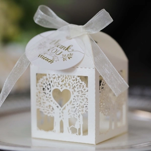 Detailed laser-cut white heart tree wedding favor box with a silk ribbon and tag