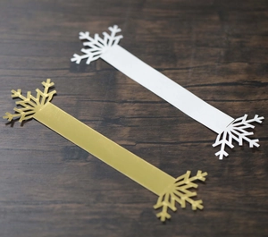 Detail of white and gold snowflake napkin rings with intricate cutout patterns for holidays