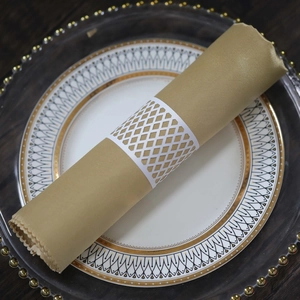 Detail of laser-cut white hollow lattice napkin ring on gold fabric and luxury dinnerware