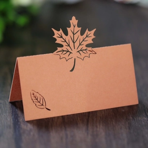 Detail of laser-cut maple leaf place card with elegant hollow design on wood background