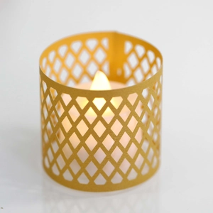 Close-up of LED flameless candle with yellow geometric cutout paper lampshade on white base