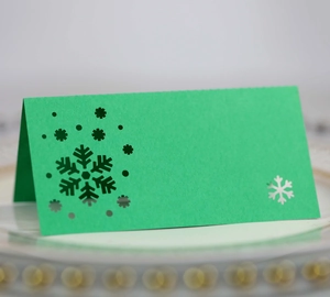 Macro shot of green Christmas table card with laser-cut snowflake patterns on a plate