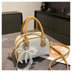 Detail of lychee pattern leather Boston bag with pearl bow and lace pendant