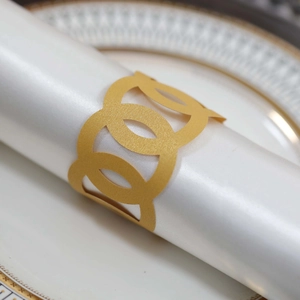 Detail of laser-cut gold hollow interlocking circles paper napkin ring for table setting