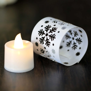 Close-up of snowflake hollow laser cut paper lampshade and warm LED candle decoration