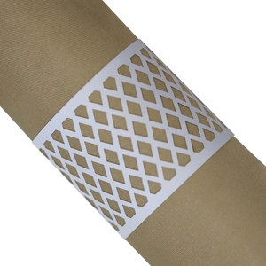 Detail of white laser-cut geometric napkin ring on champagne gold fabric napkin