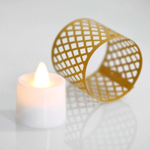 Macro detail of golden geometric lattice hollow lace sleeve for LED tea light candle