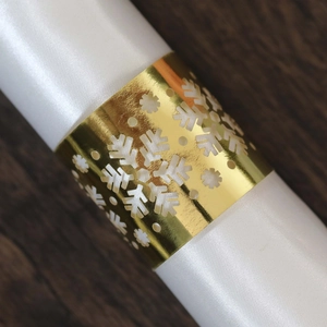 Macro detail of golden snowflake hollowed napkin ring with white silk cloth
