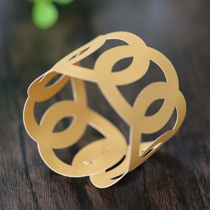 Macro view of gold laser-cut napkin ring with oval hollow pattern on dark wood background