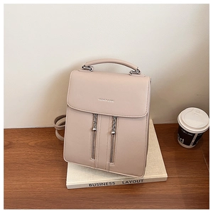 Detail of beige minimalist leather backpack with vertical zippers on a business book