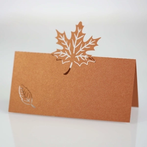 Macro shot of laser-cut maple leaf place card in pearlescent brown cardstock for weddings