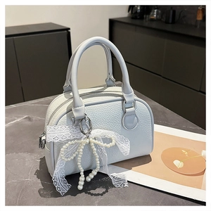 Detail of light blue Boston bag with lychee texture and pearl lace bow charm decoration