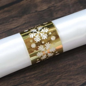 Detailed view of a gold snowflake napkin ring with laser-cut hollow pattern and silk cloth