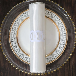 Detail of white laser-cut napkin ring with geometric patterns on a white silk napkin
