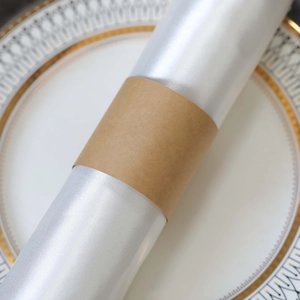 Detail of silver satin napkin with smooth texture and kraft paper ring on decorative plate