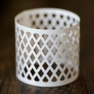 Macro detail of white hollow diamond mesh candle holder wrap with intricate paper lace texture
