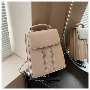 Detail of beige faux leather backpack with silver chain zippers and metallic ball pendants