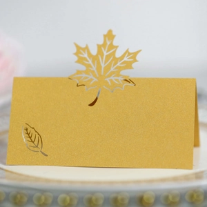 Macro detail of laser-cut golden maple leaf place card with pearlescent shimmer finish